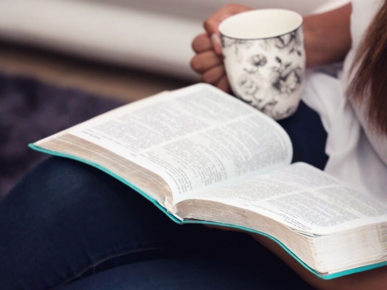 7 Ways To Grow Closer To God Person with bible open on their lap and a cup of coffee having quiet time with God