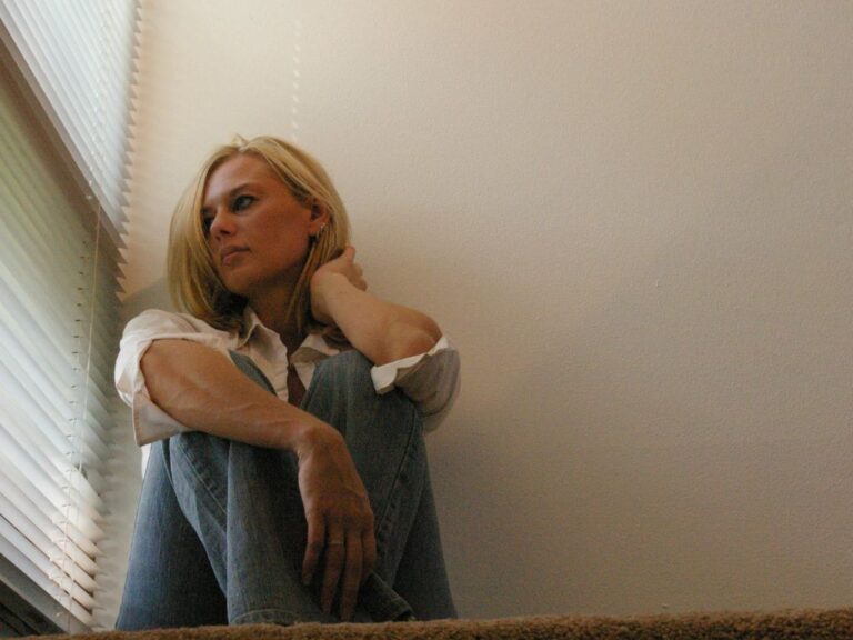 Overcoming Barriers To Being Close To God Woman sitting on the ground inside looking out a window in deep thought.
